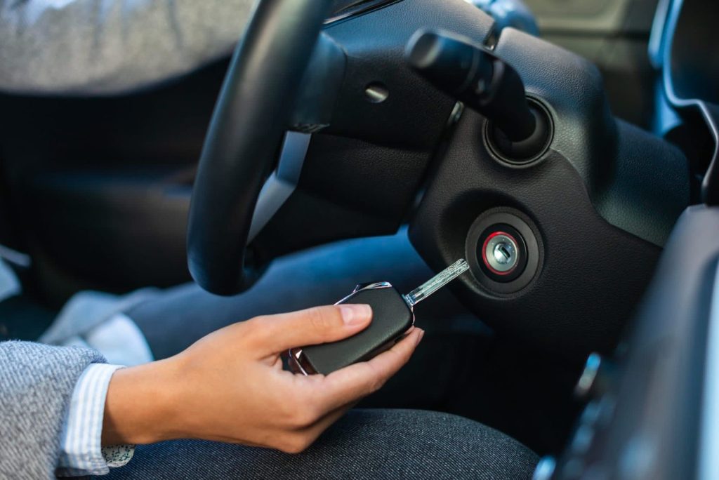 Hand inserting a car key into the ignition on the steering column