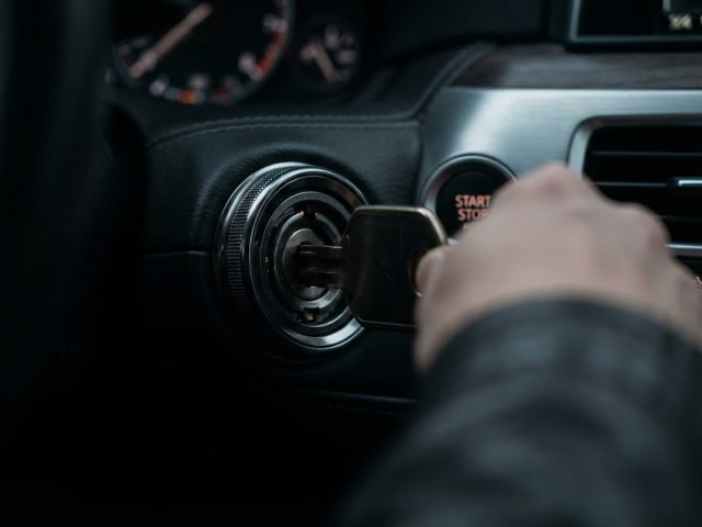 Key turning in a push-start car ignition cylinder beside the start button